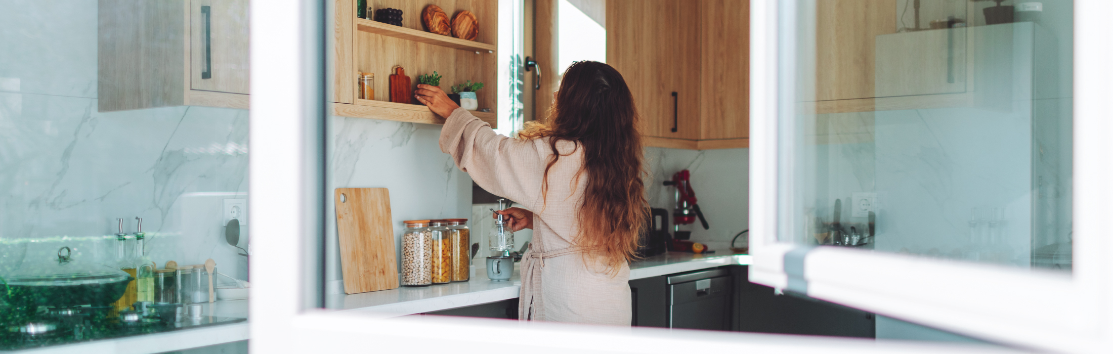 Woman in kitchen opening window