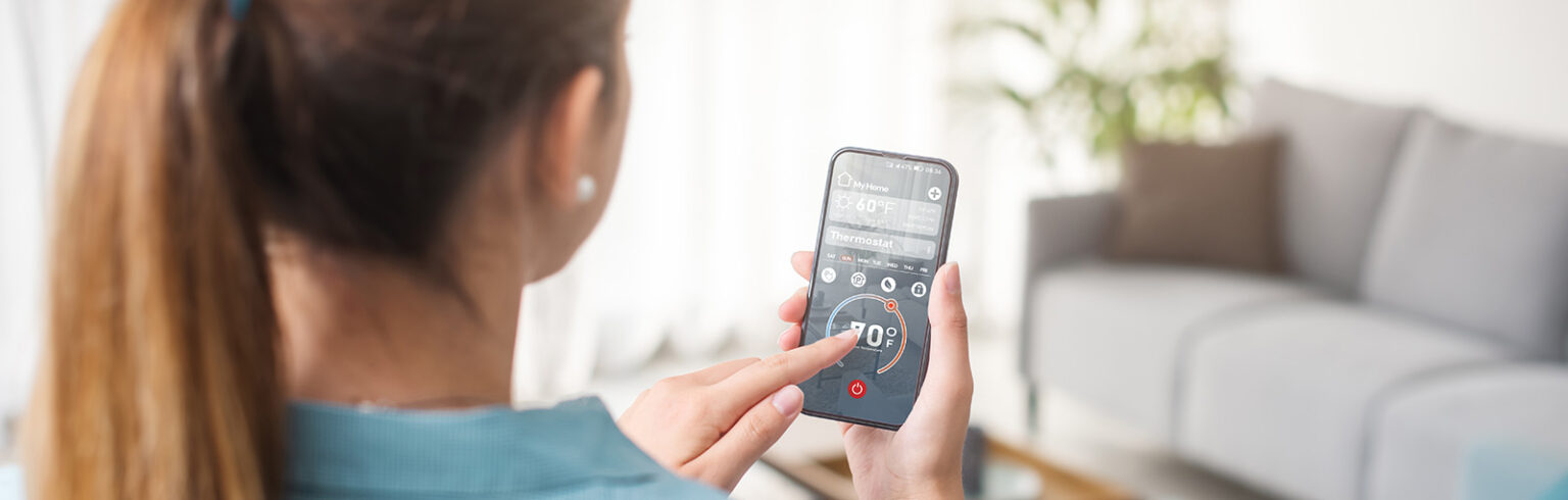 woman setting smart thermostat with her phone app